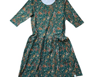 May include: A green dress with a paisley print. The dress has a round neckline and 3/4 sleeves. The skirt is gathered at the waist.