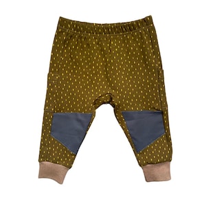 Puede incluir: Pantalones de bebé verde oliva con un estampado de puntos amarillos, rodilleras grises y puños marrones. Estos pantalones tienen un corte holgado y una cintura elástica cómoda, perfectos para el uso diario.