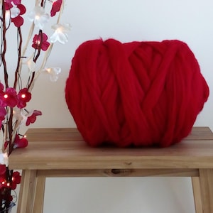 May include: A large ball of bright red yarn, ideal for knitting or crocheting chunky blankets or throws.