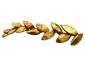 May include: A gold-toned metal brooch in the shape of a laurel wreath. The leaves are textured and have a slightly irregular shape.