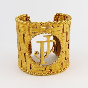 May include: Gold-toned cuff bracelet with a woven design and a large, cutout initial "F" in the center.