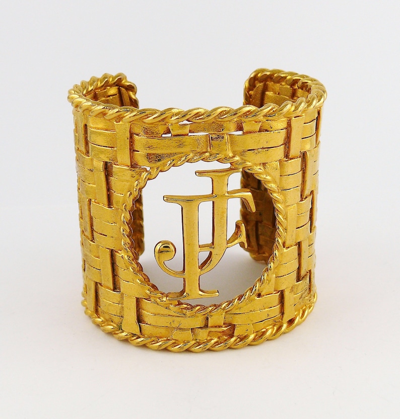 May include: Gold-toned cuff bracelet with a woven design and a large, cutout initial "F" in the center.