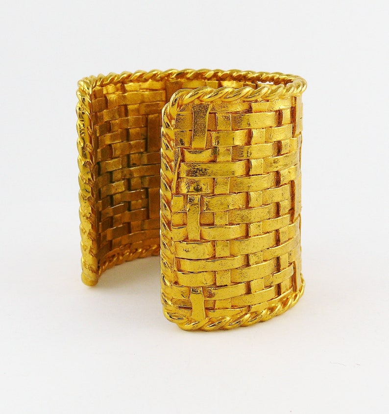 May include: A gold-tone woven cuff bracelet with a rope-like edge.