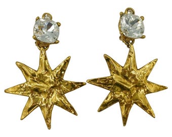 May include: Gold star-shaped earrings with clear crystal accents.