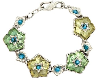 Könnte beinhalten: Ein silbernes Armband mit einem Gliederketten-Design und blütenförmigen Anhängern. Die Anhänger sind aus grünem, gelbem und klarem Glas mit blauen Akzenten. Das Armband hat einen Verschluss mit der Aufschrift "KENZO".