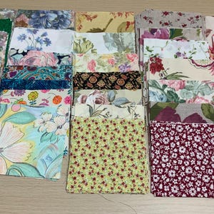 May include: A collection of square fabric swatches featuring a variety of floral, botanical, and geometric patterns in diverse colours including green, pink, blue, yellow, red, and white. The fabric pieces are arranged in a grid-like formation.