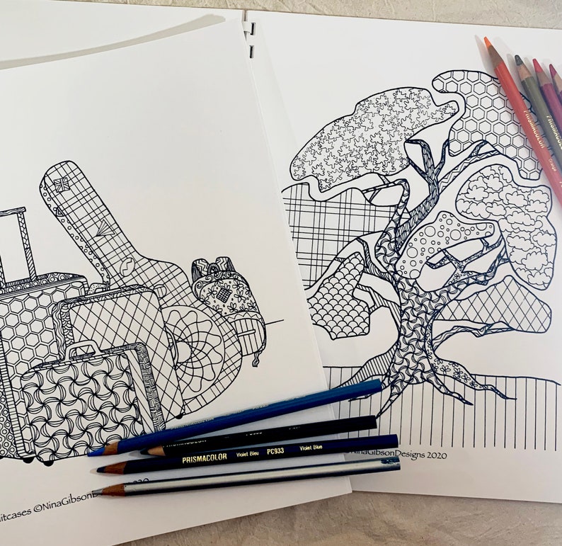 K&ouml;nnte beinhalten: Zwei Malb&uuml;cher, eines mit einem Baum und das andere mit Gep&auml;ck und einer Gitarre, liegen auf einem Tisch.  Auf dem Tisch liegen verschiedene farbige Bleistifte.