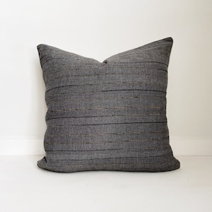 May include: A gray striped pillow with a subtle sheen. The pillow is made of a soft, textured fabric.