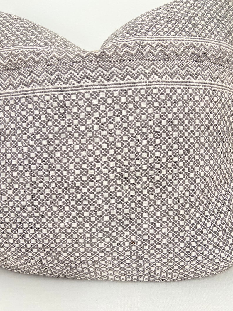 May include: A white pillow with a gray geometric pattern. The pattern is a combination of small squares and zigzags.