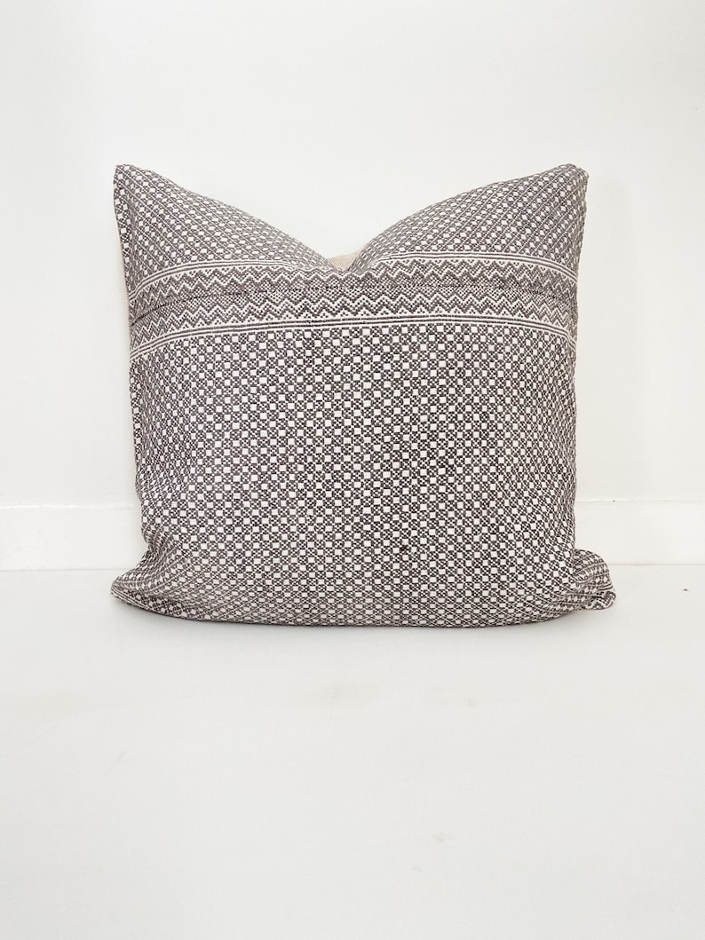 May include: A black and white patterned throw pillow with a geometric design. The pillow is made of a soft, woven fabric.