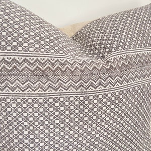 May include: A gray and white patterned pillow with a geometric design. The pillow is made of a soft, woven fabric.