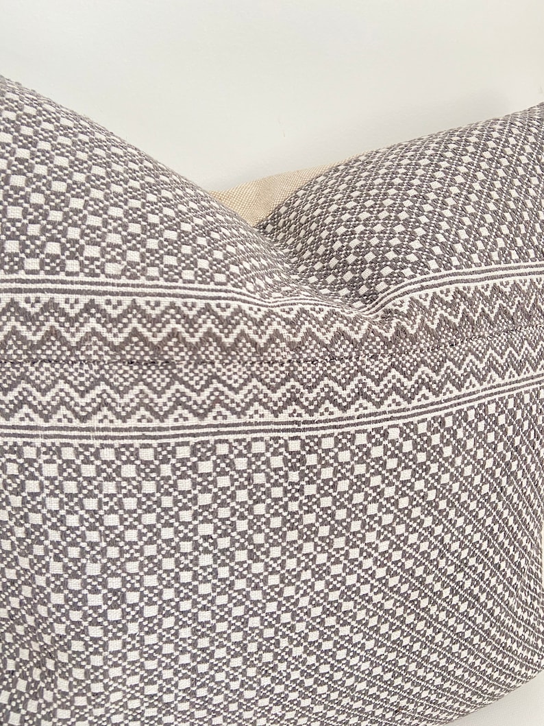 May include: A gray and white patterned pillow with a geometric design. The pillow is made of a soft, woven fabric.