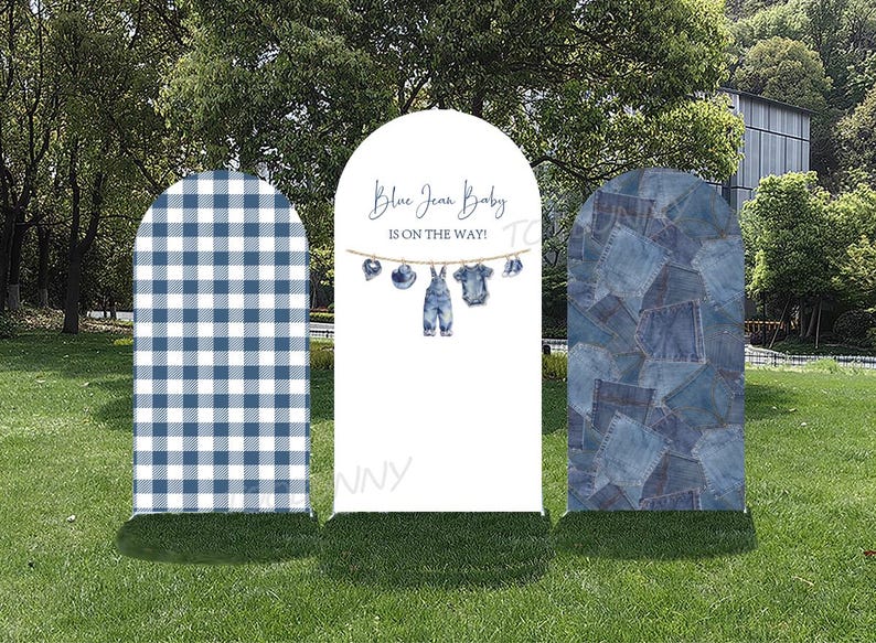 May include: Three outdoor signs with arched tops. The left sign has a blue and white gingham pattern. The center sign reads "Blue Jean Baby is on the way!" with baby clothes illustrations. The right sign has a patchwork denim design.