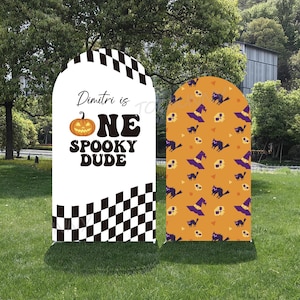 Może przedstawiać: Dwa znaki ogrodowe o tematyce Halloween. Jeden biały znak zawiera grafikę dyni i tekst "Dimitri is ONE Spooky Dude" z czarno-białym wzorem w szachownicę. Drugi znak ma pomarańczowe tło z grafiką Halloween.
