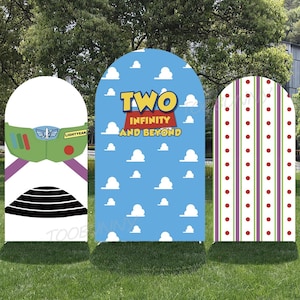Op de afbeelding: Drie decoratieve boogvormige borden met cartoonontwerpen. Eén bord heeft een Buzz Lightyear-ontwerp, een ander heeft de tekst "TWO INFINITY AND BEYOND" op een blauwe achtergrond met wolken, en de derde heeft een gestreept patroon.