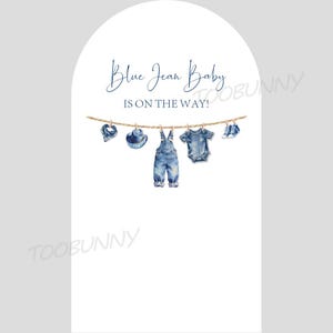 May include: A watercolor illustration on a white background features baby clothes hanging on a clothesline. The clothes include a bib, hat, overalls, onesie, and shoes, all in denim blue. The text "Blue Jean Baby IS ON THE WAY!" is written above the clothes.