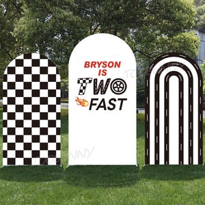 May include: Three arched racing-themed signs. One features a black and white checkered pattern, another reads "Bryson is Two Fast" with a race car wheel and flames, and the third has a road design with white lines.