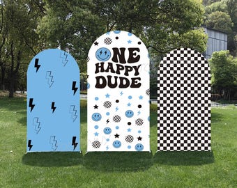 May include: Three arched signs with a retro theme. One is light blue with black lightning bolts, the center sign is white with the text "ONE HAPPY DUDE" and smiley faces, and the third is a black and white checkerboard pattern.