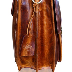 May include: A brown leather briefcase with a brass buckle and a leather tag that says "Kulattiny London".