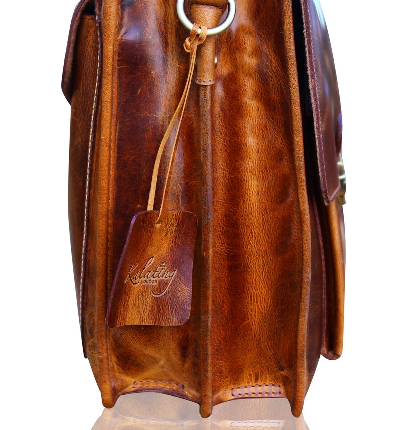 May include: A brown leather briefcase with a brass buckle and a leather tag that says "Kulattiny London".