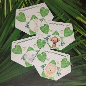 May include: Four white paper diaper-shaped cards with scalloped edges. Each card features a different jungle animal: a giraffe, a monkey, an elephant, and a lion. Each card has a green leaf design and a white button.