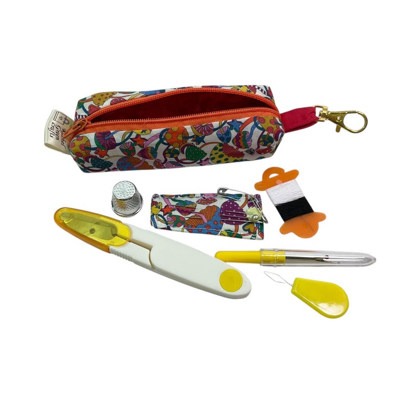May include: A small zippered pouch with a colorful mushroom print, a metal thimble, a fabric needle case, a spool of black and white thread, a yellow seam ripper, a yellow needle threader, and a yellow marking pen with a clear cap.