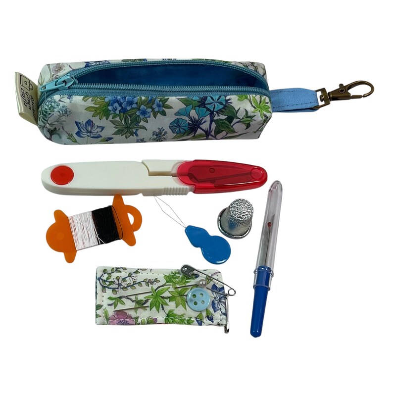 May include: A floral print fabric sewing kit case with a blue zipper and lobster clasp. Included are white and black thread on an orange spool, a red and white seam ripper, a blue needle threader, a metal thimble, a blue seam ripper, and a needle case.