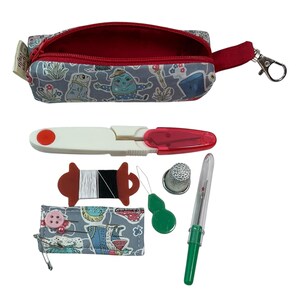 May include: A gray fabric zippered pouch with a whimsical character print, containing a white and red seam ripper, a spool of black and white thread, a silver thimble, a green needle threader, and a small fabric needle case with pins.