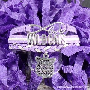 May include: Purple and white layered bracelet with a silver charm that says "love" and "Wildcats". The charm is a silver wildcat head.