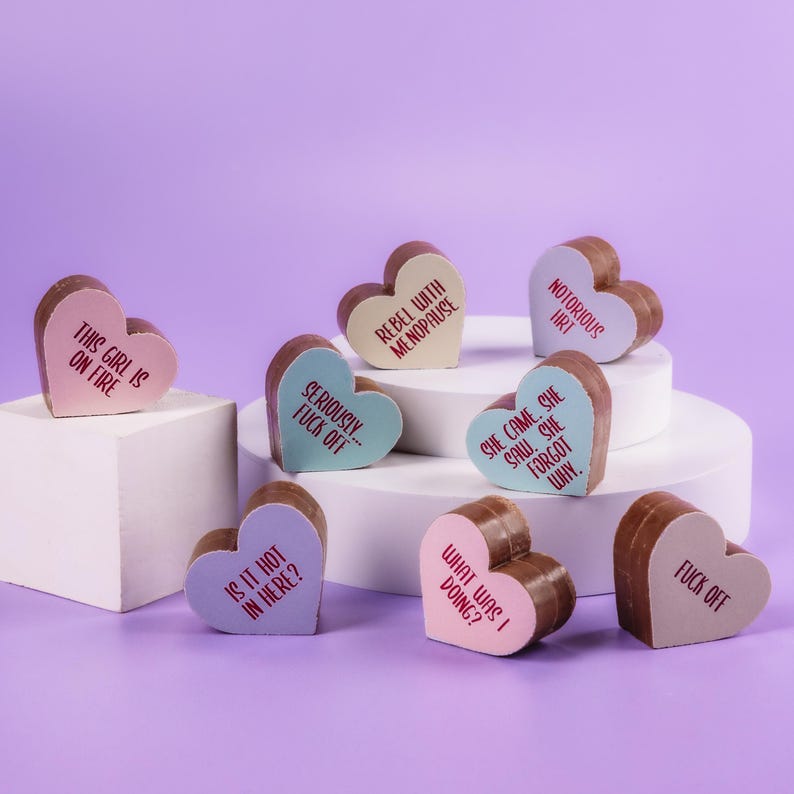 Pastel-decorated menopause chocolates from Bagstock & Bumble on plinths, decorated with phrases like 'Rebel with menopause' and 'This girl is on fire.'