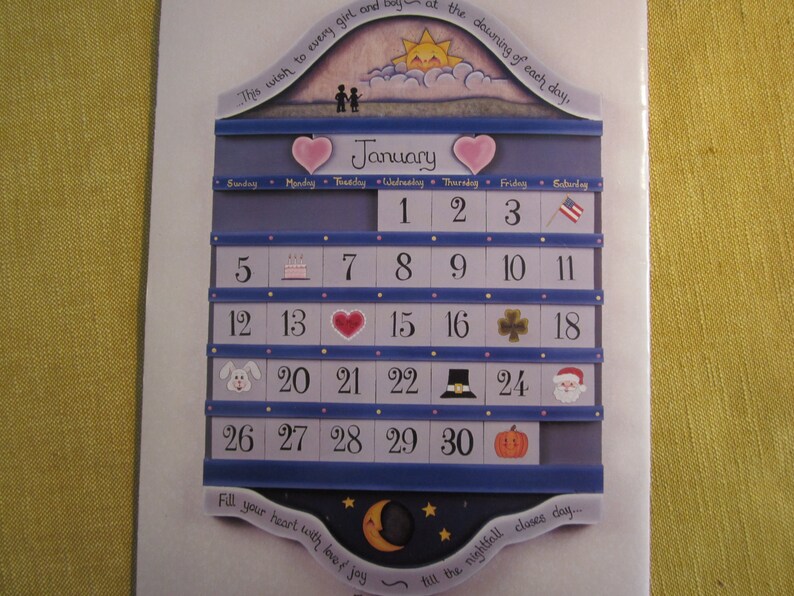 May include: A blue and white wooden calendar with a heart-shaped design. The calendar is for January and features a different icon for each day. The text "This wish to every girl and boy at the dawning of each day" is at the top of the calendar.