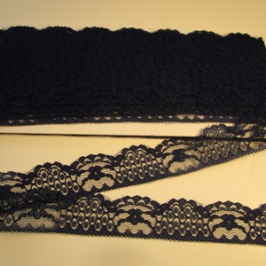 May include: Black lace trim with a scalloped edge. The lace has a delicate floral pattern.