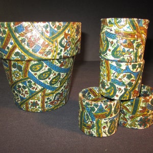 May include: A set of four small terracotta flower pots with a colorful paisley pattern. The pots are stacked on top of each other, with the largest pot at the bottom and the smallest pot at the top.