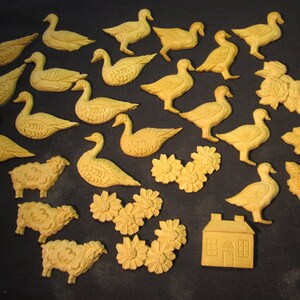 May include: A collection of 20 ceramic figurines of geese and floral designs. The geese are in various poses, some with their wings spread and others with their heads down. The floral designs are in a variety of colors and shapes.