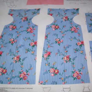 May include: A sewing pattern for a dress with a blue and white striped fabric with pink floral accents. The pattern includes instructions for sewing the dress and a diagram of the dress.