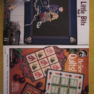 May include: Two quilt pattern books, one titled "Little Bits Book 2" with a blue and white quilt featuring a boy and girl, and the other titled "No-Sew Quilts!" with a green and white quilt featuring bunnies and a brown and white quilt featuring houses and trees.