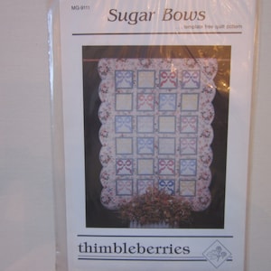 May include: A quilt pattern titled "Sugar Bows" with a template-free design. The pattern features a quilt with a scalloped border and a central design of colorful bows. The pattern is from Thimbleberries.