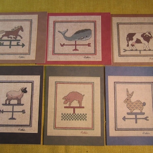 May include: Six framed cross-stitch designs featuring various animals on a weathervane. The animals include a horse, whale, cow, sheep, pig, and rabbit. Each design is framed in a different color.