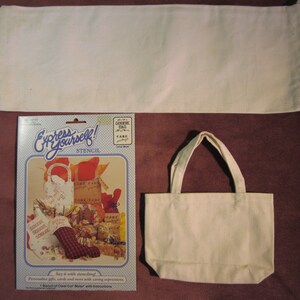 May include: A white canvas tote bag with a stencil kit for decorating gift bags. The kit includes a stencil with the words "Express Yourself!" and a design of a gift bag with the words "Care Care" on it. The kit also includes a sheet of clear-cut Mylar with instructions.