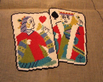 May include: Needlepoint playing card designs featuring a red-clad figure with a heart symbol and a queen with a spade symbol. The cards are stitched with various colors, including red, blue, green, and yellow, and have a black border.