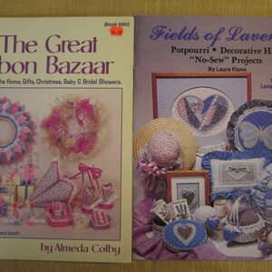 May include: Two craft books with colorful covers. The Great Ribbon Bazaar features a pink and blue ribbon wreath and other ribbon crafts. Fields of Lavender features a lavender-colored heart and other lavender-themed crafts. Both books feature the words "No-Sew" projects.