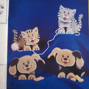 May include: Four wooden animal figurines, a cat, a tiger, and two dogs, are arranged on a blue background. The cat and tiger are playing with a ball of yarn. The dogs are playing with a bone.