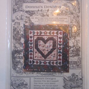 May include: A quilting pattern for a mini log cabin heart quilt with an applique border of hearts and flowers. The pattern is titled "Donna's Designs" and includes instructions for making a quilt with a brown background and red, green, and blue accents.