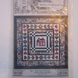 May include: A quilting pattern for a nine-patch house quilt with a floral border. The pattern is called "Nine Patch House with Floral Border" and is size 24 inches by 24 inches.