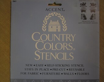 May include: A blue and white package for Country Colors Stencils. The package features a white house with a wreath and the text "Country Colors Stencils". The package also includes the text "New, Easy, Self-Sticking Stencil, Stays in Place, Pre-Cut, Reusable, For Fabric, Furniture, Walls, Floors".