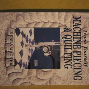 May include: Book cover with the title "Teach Yourself Machine Piecing & Quilting" by Debra Wagner. The cover features a close-up of a sewing machine needle and a quilt pattern.
