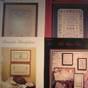 May include: Four different cross-stitch sampler patterns. The first pattern is titled "A Sampler of Love" and features a bluebird design. The second pattern is titled "Trust in Thee Sampler" and features a floral design with a verse about trust. The third pattern is titled "Fireside Samplers" and features a floral design with a verse about the pleasures of home. The fourth pattern is titled "We Sisters Three" and features a floral design with a verse about sisterhood.