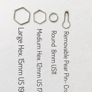 May include: Four silver-toned crochet hooks: a large hexagon hook (15mm, US 19), a medium hexagon hook (12mm, US 17), a round hook (8mm, US 11), and a removable pear-shaped crochet pin.