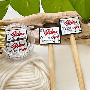 May include: Wine-themed cocktail picks with the text "It's Wine O'Clock Somewhere" in red script. The picks feature a square design with wine glasses. Some picks are in a clear container, others are on wooden sticks.