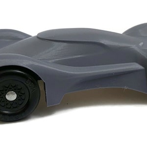 May include: A gray, streamlined race car model with black wheels. The car has a sleek, aerodynamic design and is made of a smooth, durable material.